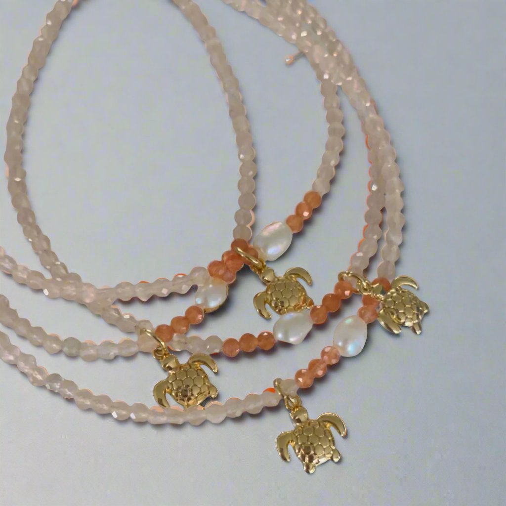 Light colored anklets with tiny golden sea turtle charms